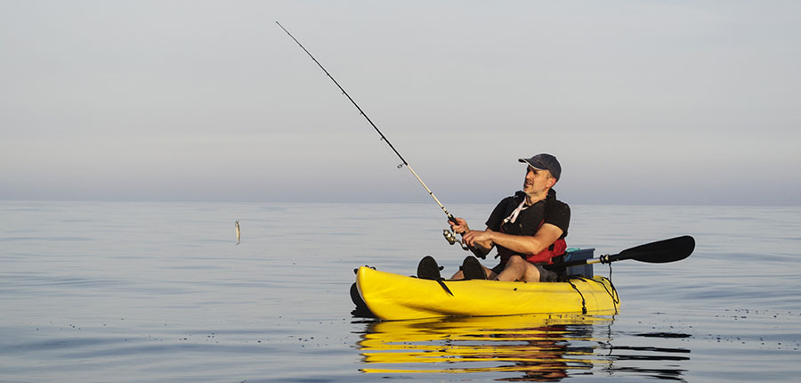 man fishing in kayak on lake