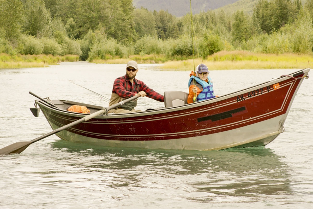 father and son fishing from drift boat on alaska river