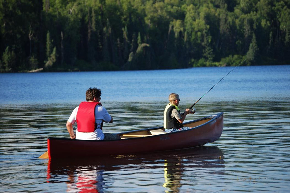 father with son fishing from canoe in a lake