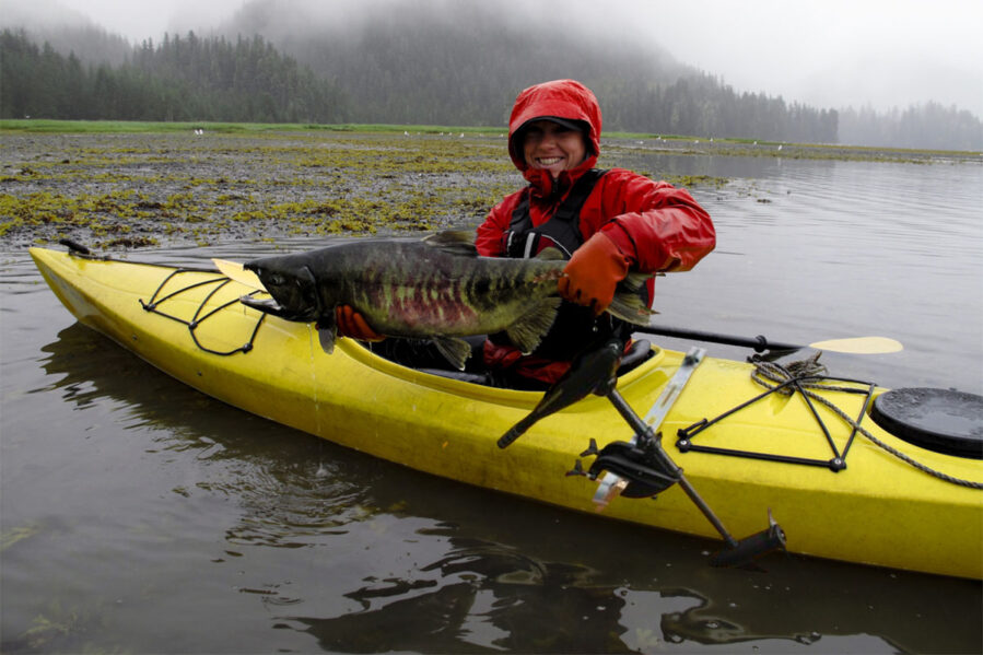 fishing kayak with side mount trolling motor. Angler with salmon catch.